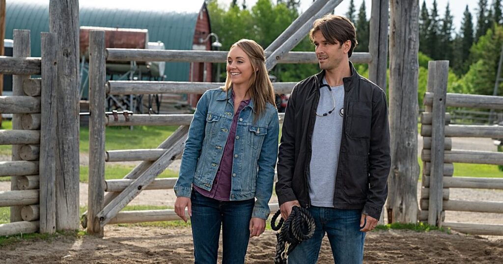 Amber Marshall as Amy Fleming and Graham Wardle as Ty Borden standing together at the ranch corral on Heartland