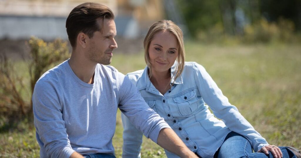 Graham Wardle as Ty Borden and Amber Marshall as Amy Fleming sitting together in the grass on Heartland