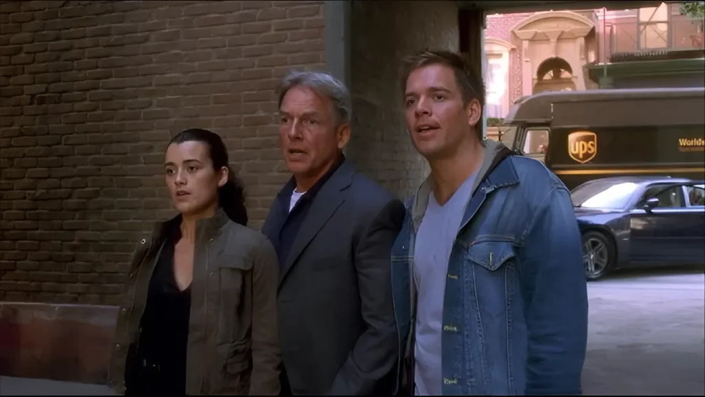 Ziva David, Leroy Jethro Gibbs, and Anthony DiNozzo stand side by side in an NCIS alleyway scene, looking ahead with focused expressions.