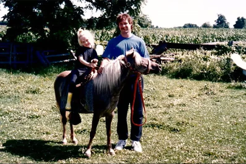 A young Amber Marshall learns how to ride a horse.